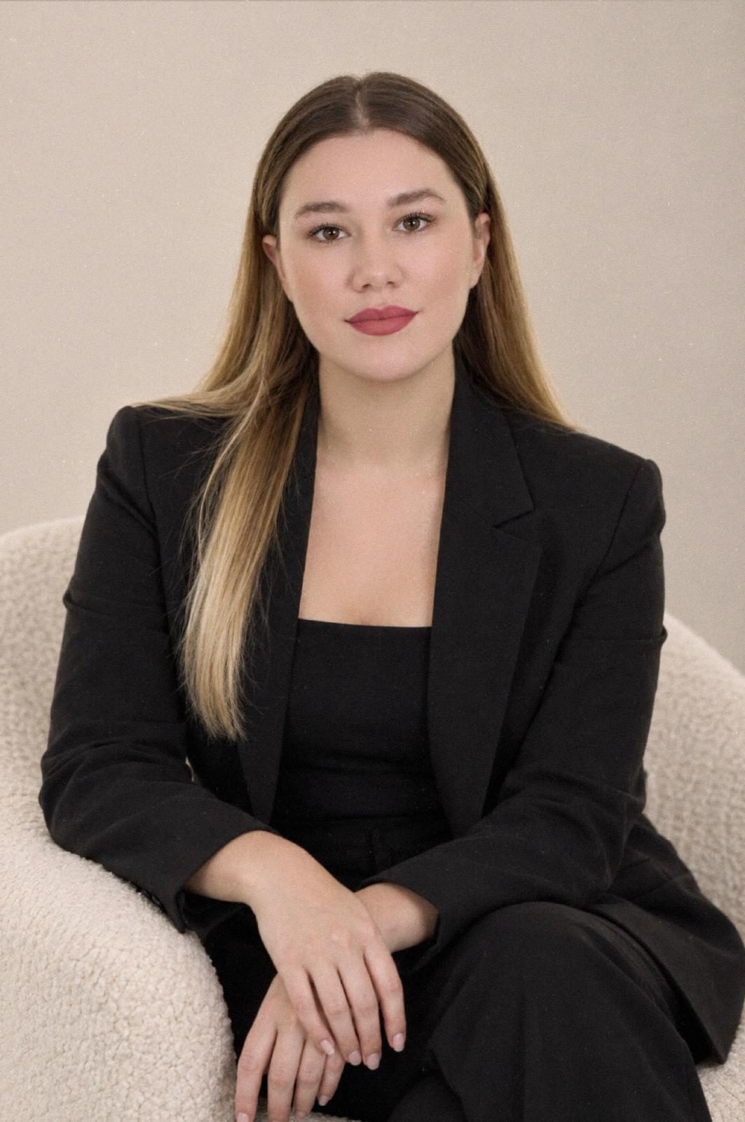 Ksara, founder of Portraits Nail Studio, smiling at a marble desk in the studio