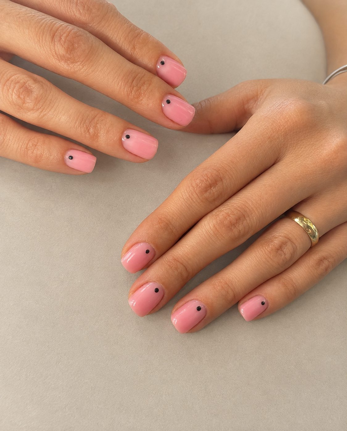 Pink nails finished with a single small black dot on each nail
