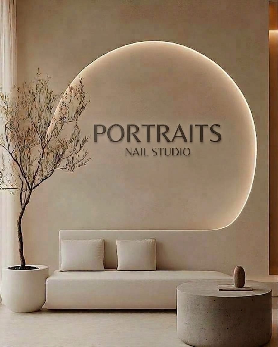 The Portraits Nail Studio reception, with the Portraits Nail Studio sign on a softly lit curved wall above a cream sofa